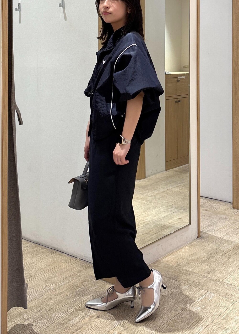 グレー系のショルダーバッグ、ブルー系のスカート、シルバー系のパンプスを着用したレディースの春コーディネートの4枚目の写真