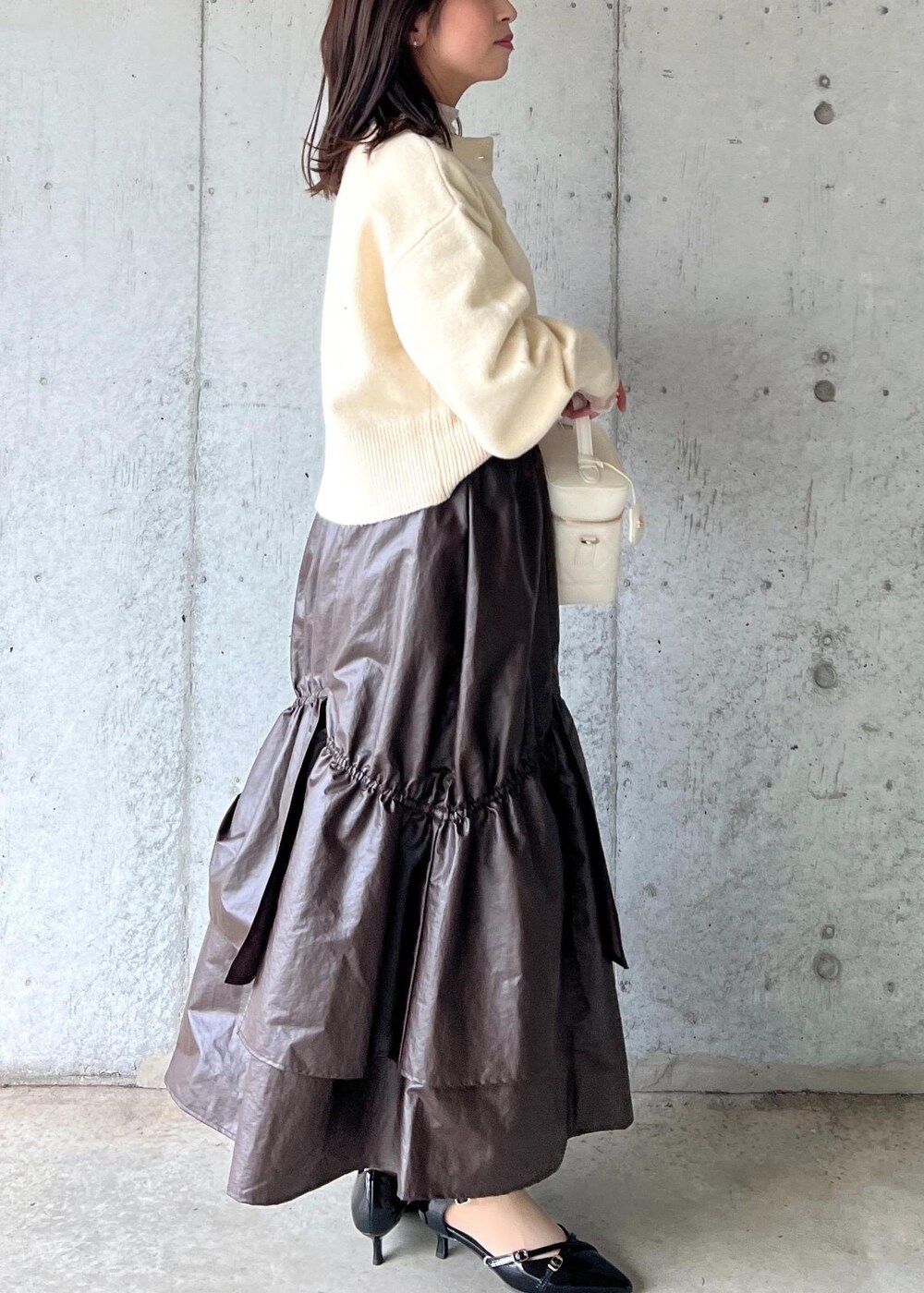 ブラウン系のスカート、ベージュ系のTシャツ/カットソー、ブラック系のパンプスを着用したレディースの冬コーディネートの5枚目の写真