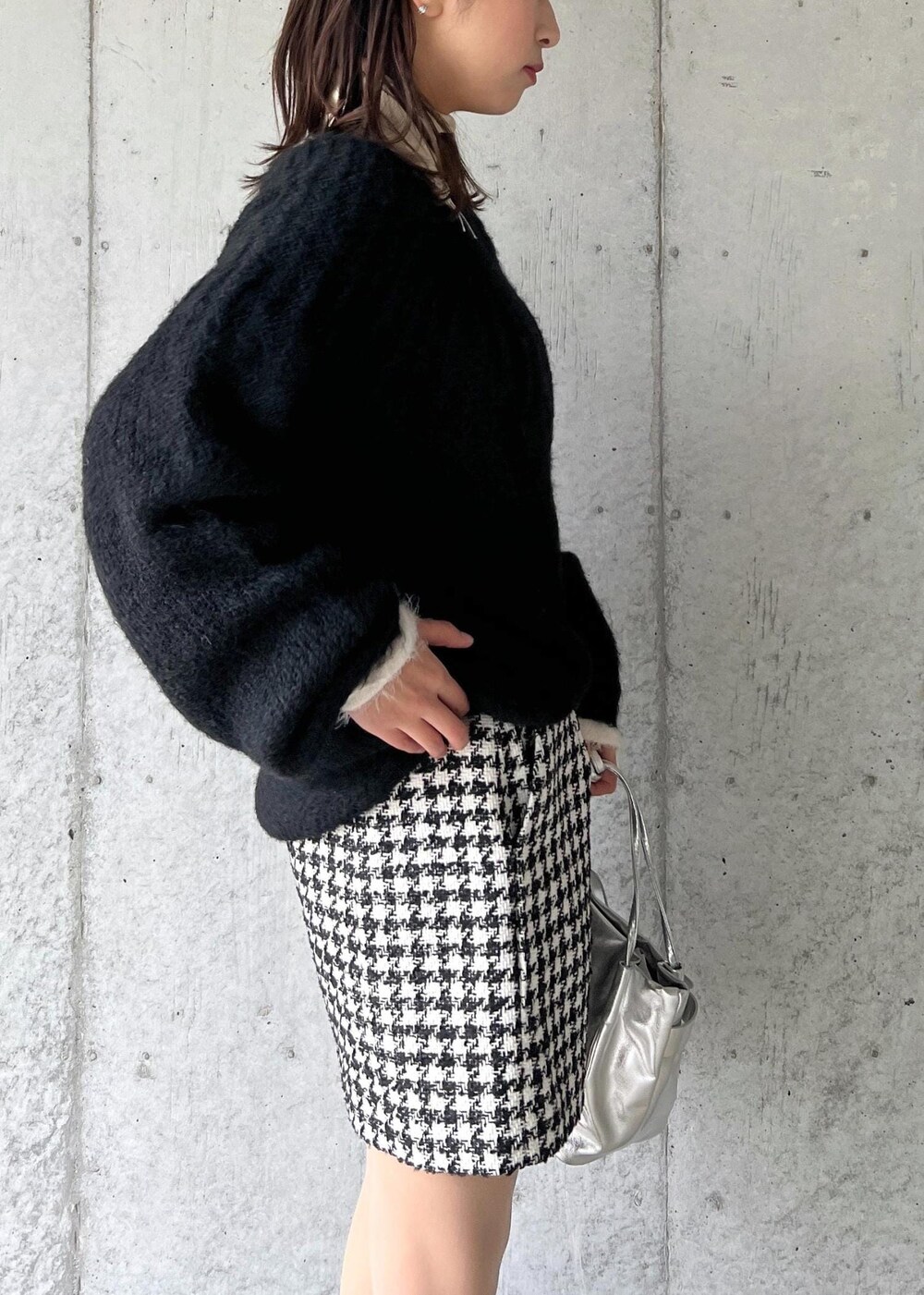 シルバー系のブーツ、ブラック系のスカート、ホワイト系のニット/セーターを着用したレディースの冬コーディネートの8枚目の写真