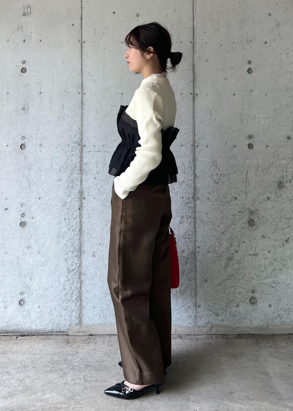 レッド系のショルダーバッグ、ブラック系のパンプス、ホワイト系のニット/セーターを着用したレディースの冬コーディネートの2枚目の写真