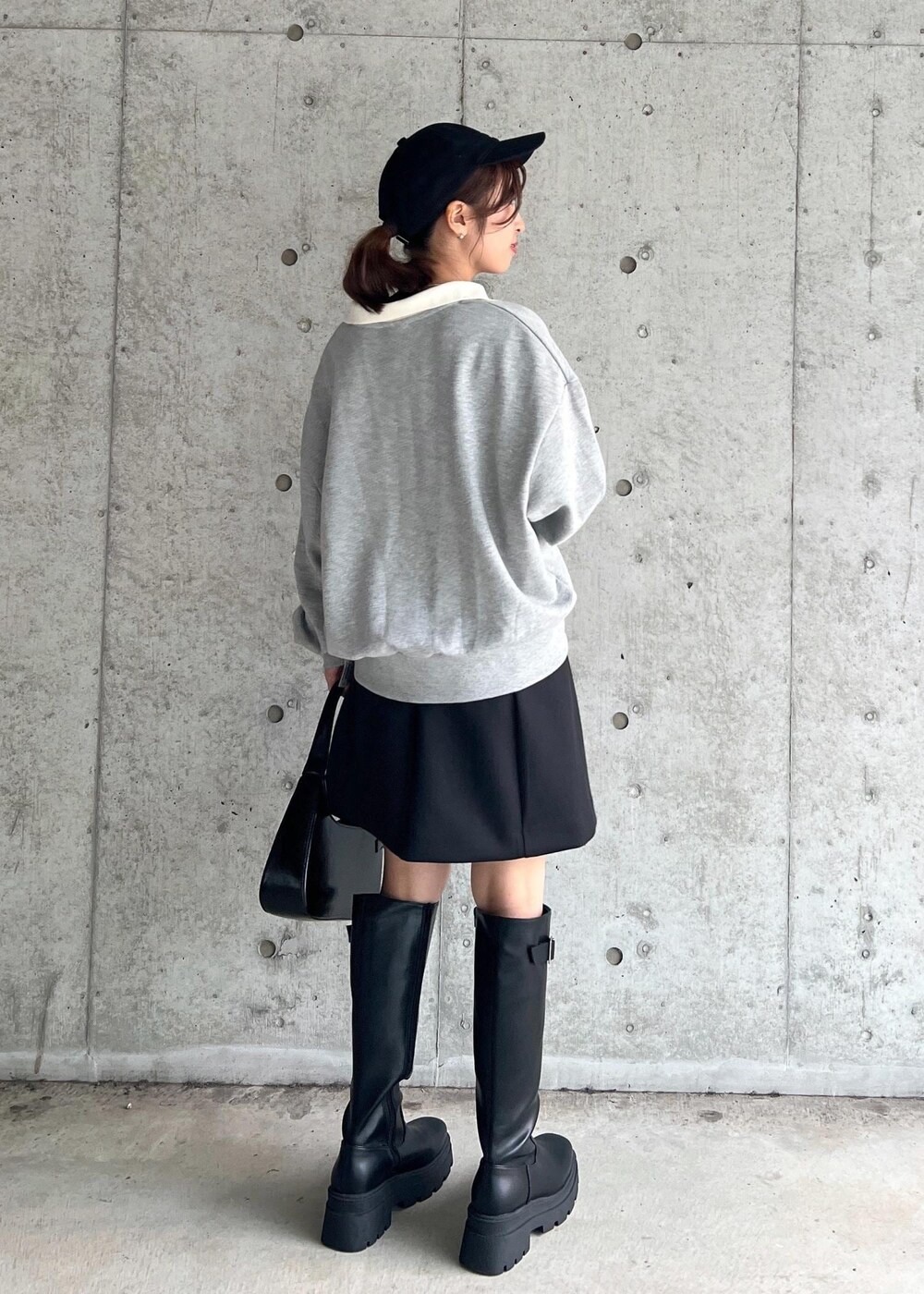 ブラック系のブーツ、ブラック系のハンドバッグ、ブラック系のスカートを着用したレディースの秋コーディネートの4枚目の写真