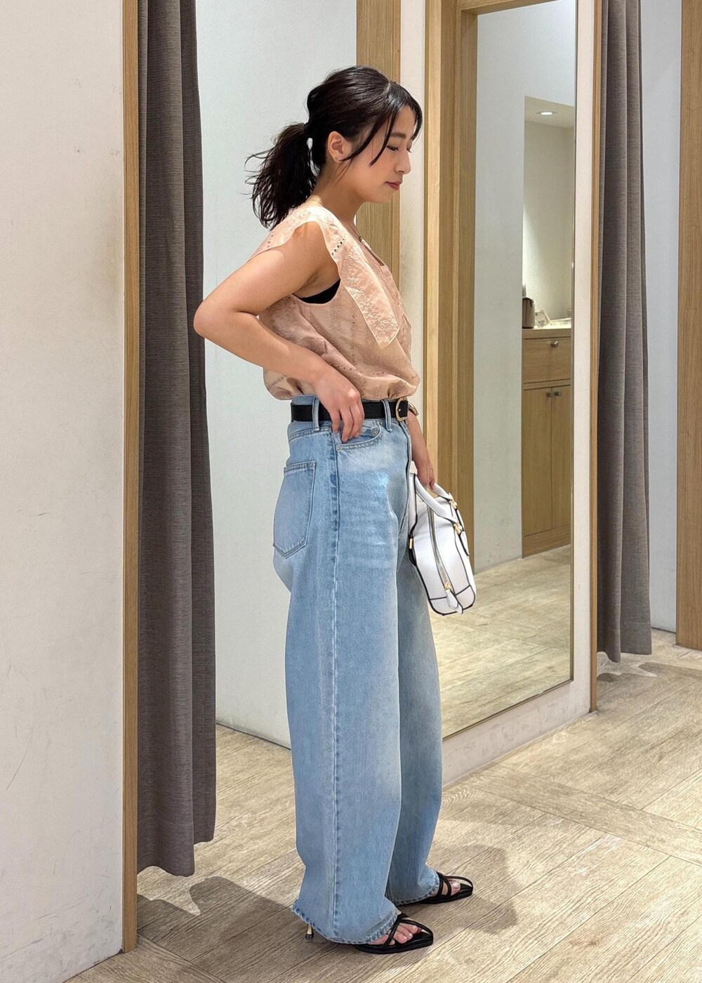 ブルー系のデニムパンツ、ブラック系のサンダル、ブラック系のショルダーバッグを着用したレディースの夏コーディネートの4枚目の写真