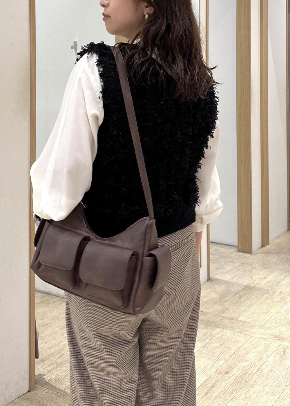 ベージュ系のスラックス、ブラウン系のショルダーバッグ、ブラック系のベストを着用したレディースの秋コーディネートの8枚目の写真