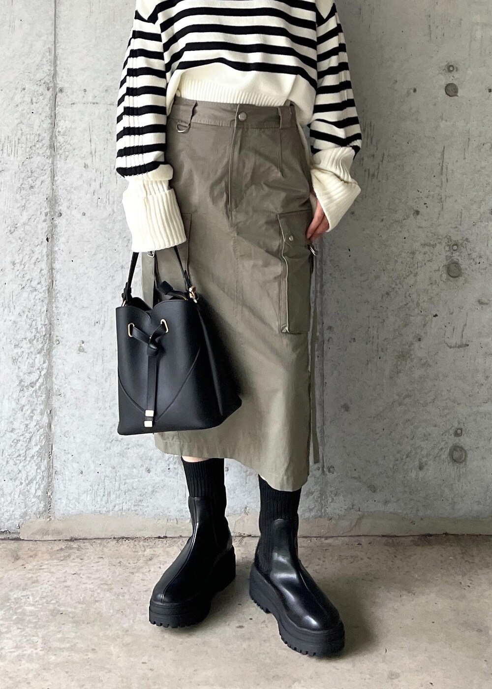 ブラック系のブーツ、グリーン系のスカート、ホワイト系のニット/セーターを着用したレディースの秋コーディネートの10枚目の写真