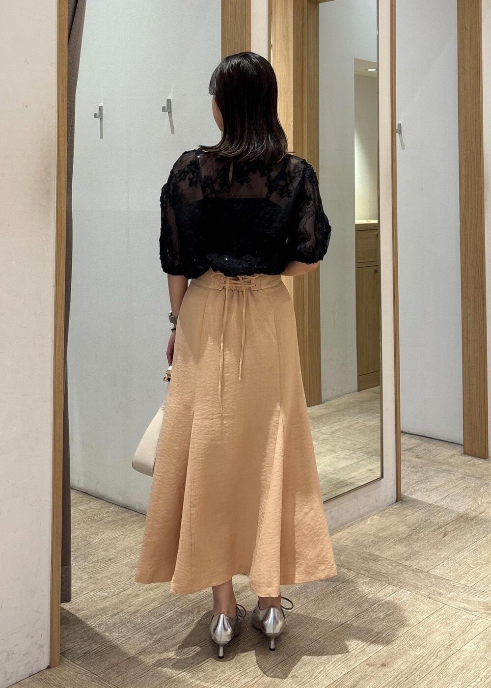 ホワイト系のハンドバッグ、シルバー系のパンプス、オレンジ系のスカートを着用したレディースの春コーディネートの4枚目の写真