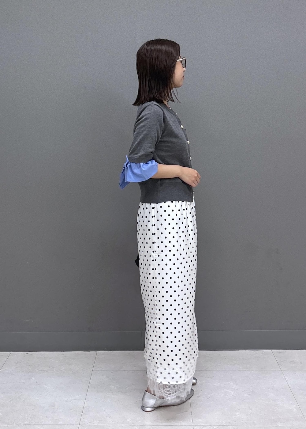 ブラック系のショルダーバッグ、シルバー系のパンプス、グレー系のカーディガン/ボレロを着用したレディースの夏コーディネートの4枚目の写真