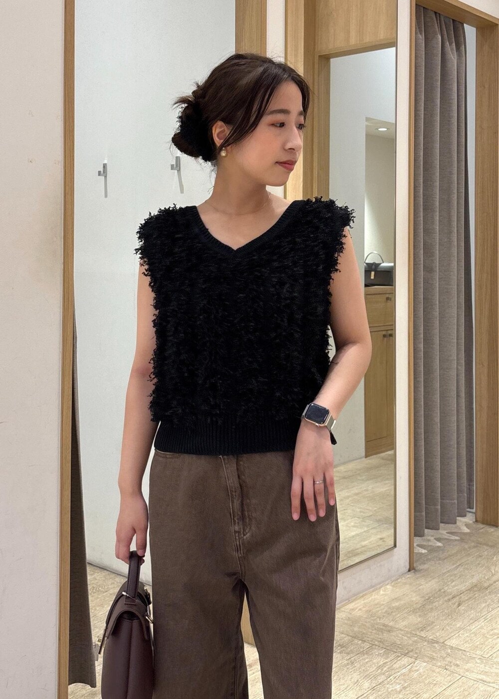 ブラウン系のショルダーバッグ、ブラック系のパンプス、ブラック系のベストを着用したレディースの秋コーディネートの4枚目の写真