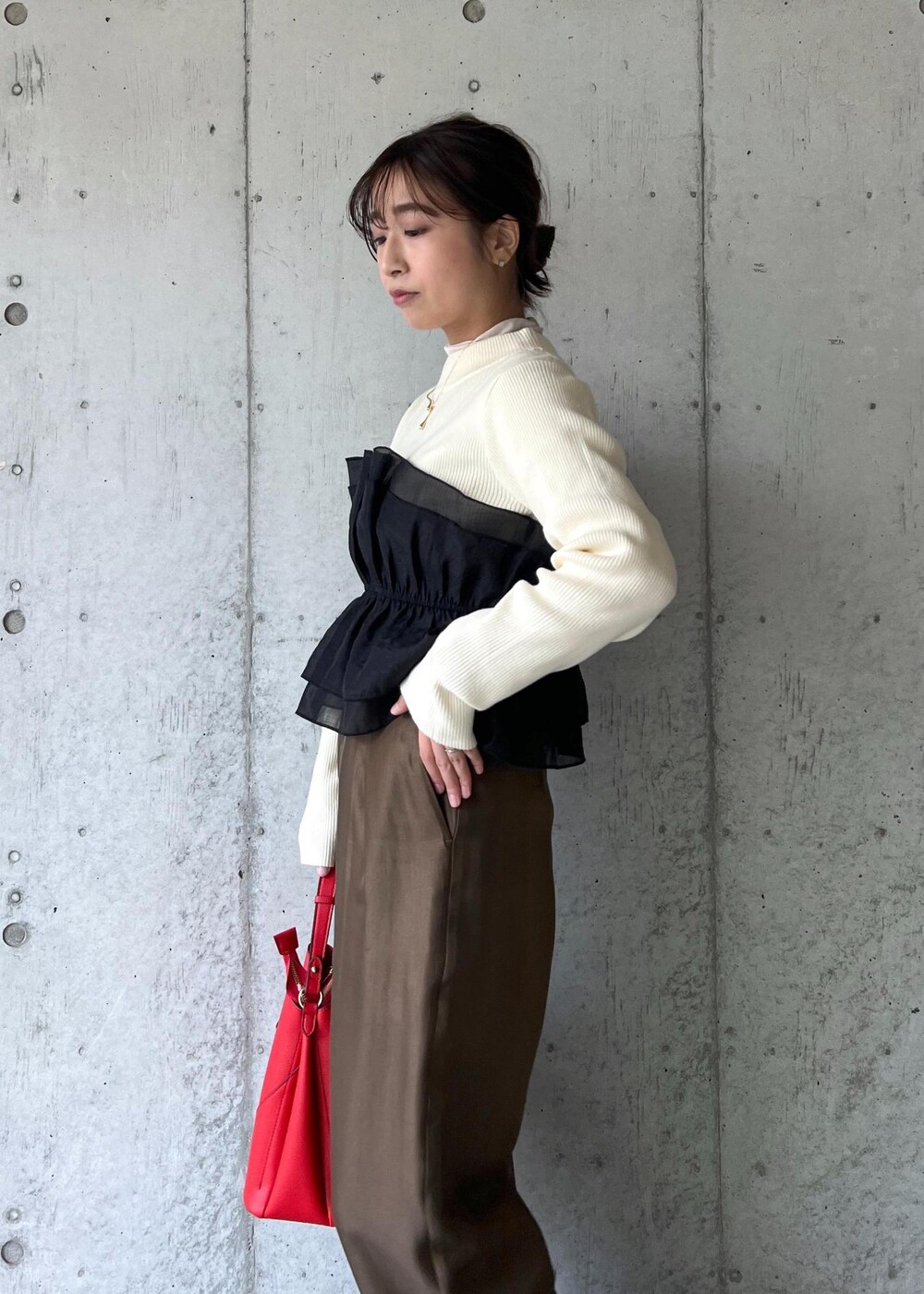 レッド系のショルダーバッグ、ブラック系のパンプス、ホワイト系のニット/セーターを着用したレディースの冬コーディネートの6枚目の写真