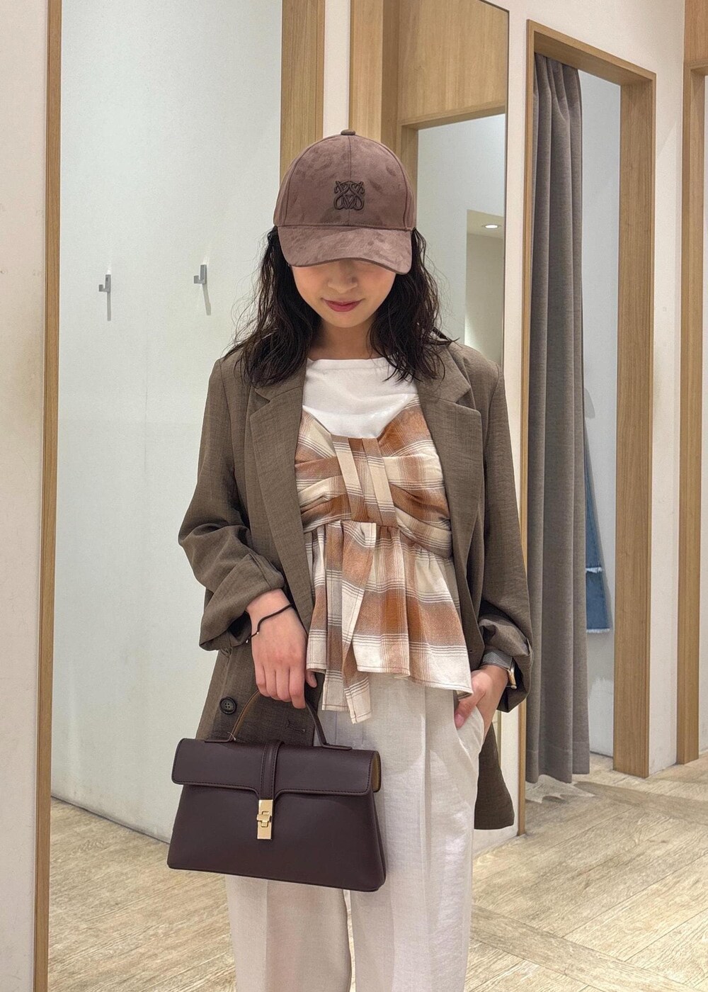 ブラウン系のショルダーバッグ、グリーン系のテーラードジャケット、ホワイト系のスラックスを着用したレディースの夏コーディネートの5枚目の写真