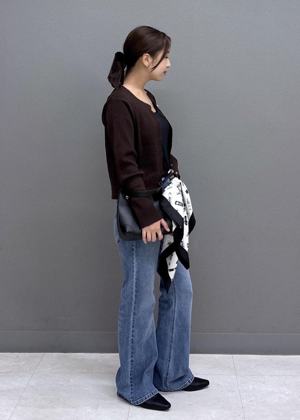 ブラック系のパンプス、ブルー系のデニムパンツ、ブラウン系のカーディガン/ボレロを着用したレディースの秋コーディネートの4枚目の写真