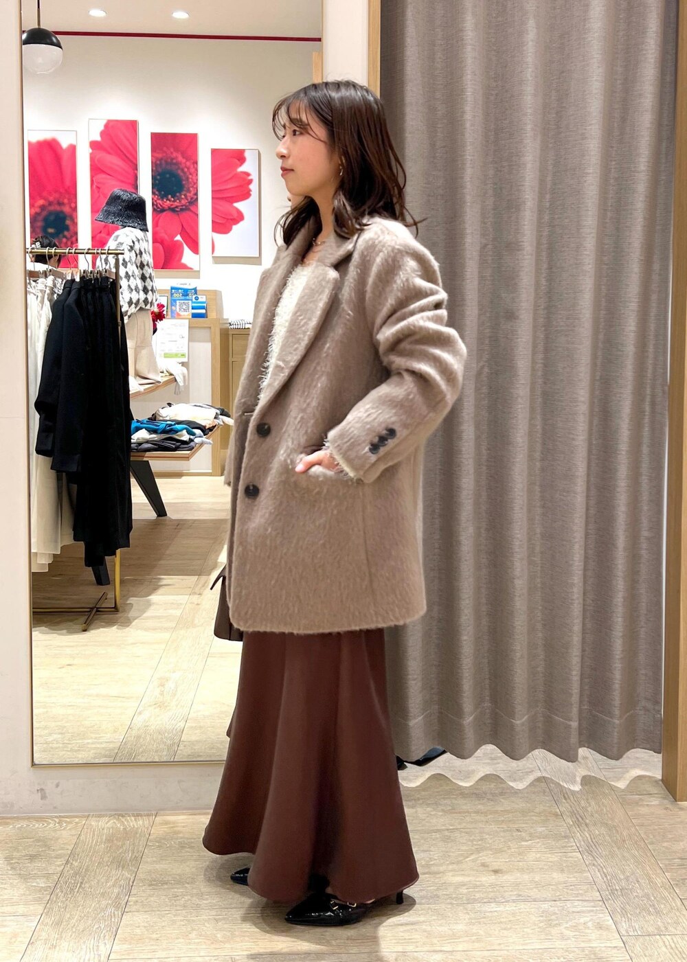 ブラック系のパンプス、ブラウン系のスカート、ホワイト系のニット/セーターを着用したレディースの冬コーディネートの2枚目の写真