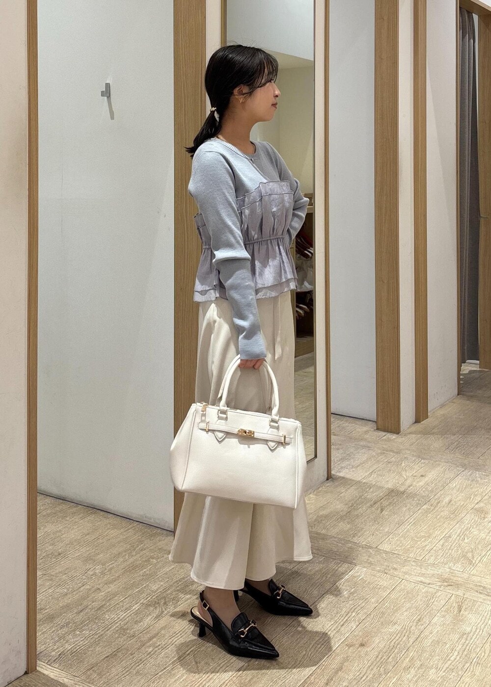 ブラック系のパンプス、ベージュ系のスカート、ブルー系のニット/セーターを着用したレディースの春コーディネートの3枚目の写真