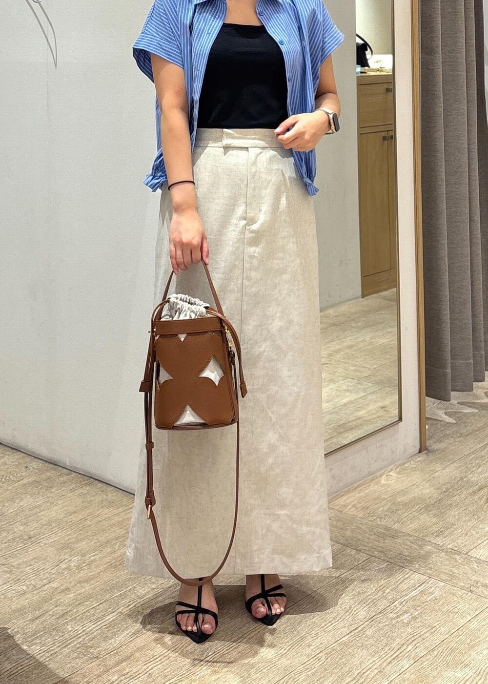 ブラック系のサンダル、ホワイト系のスカート、ブルー系のシャツ/ブラウスを着用したレディースの夏コーディネートの9枚目の写真