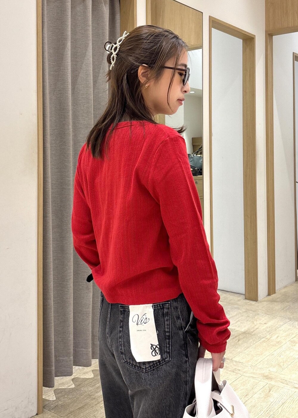 ブラウン系のパンプス、レッド系のカーディガン/ボレロ、ブラック系のデニムパンツを着用したレディースの春コーディネートの8枚目の写真