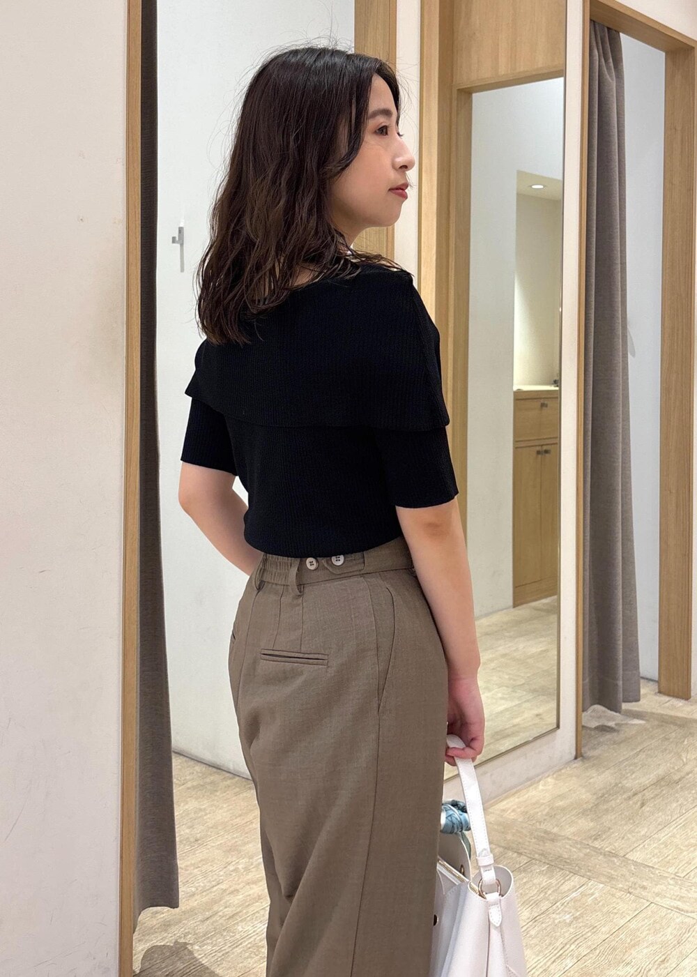 ホワイト系のショルダーバッグ、グリーン系のスラックス、ブラック系のニット/セーターを着用したレディースの夏コーディネートの6枚目の写真