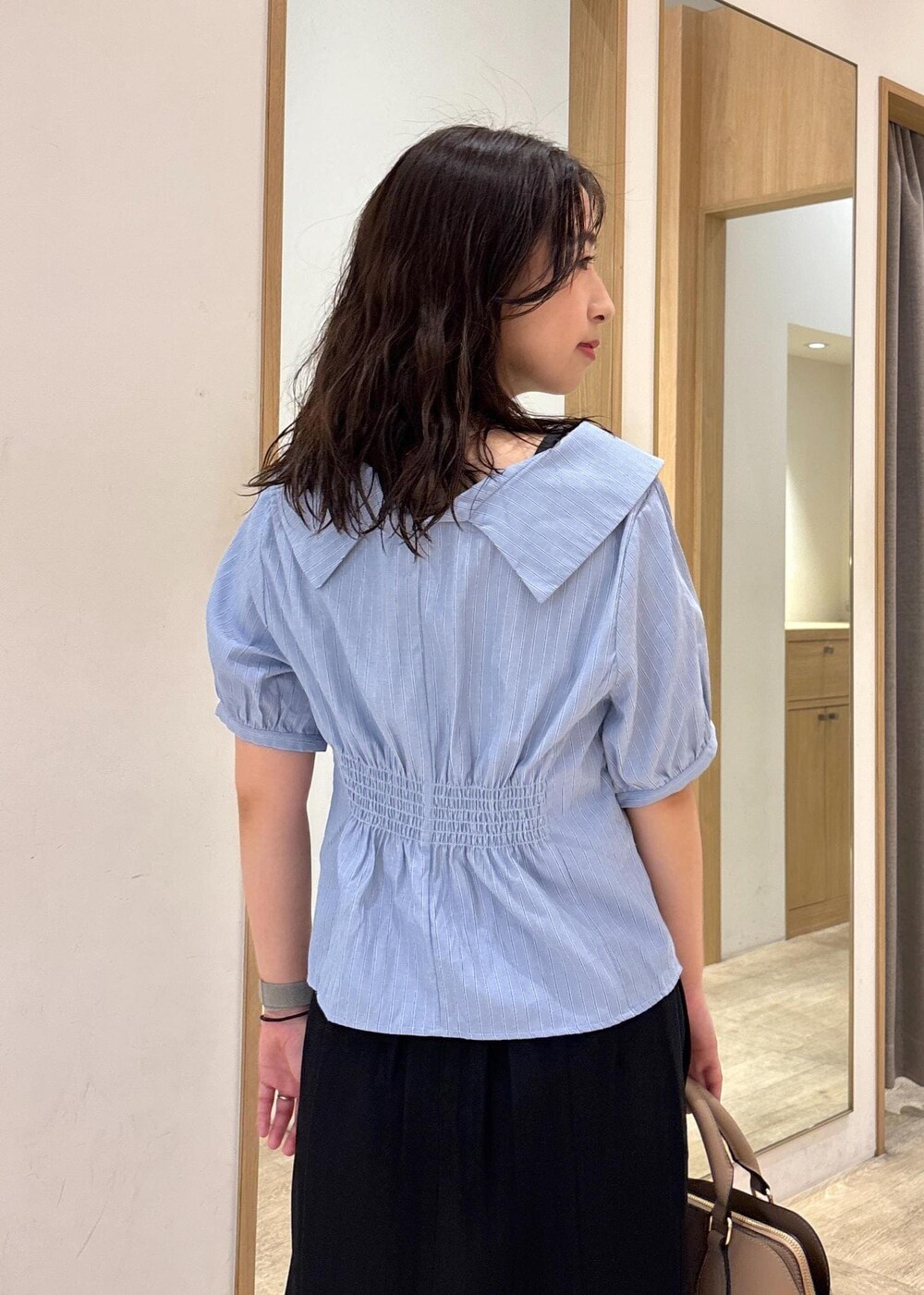 ベージュ系のボストンバッグ、ブラック系のスカート、ブラック系のローファーを着用したレディースの秋コーディネートの7枚目の写真