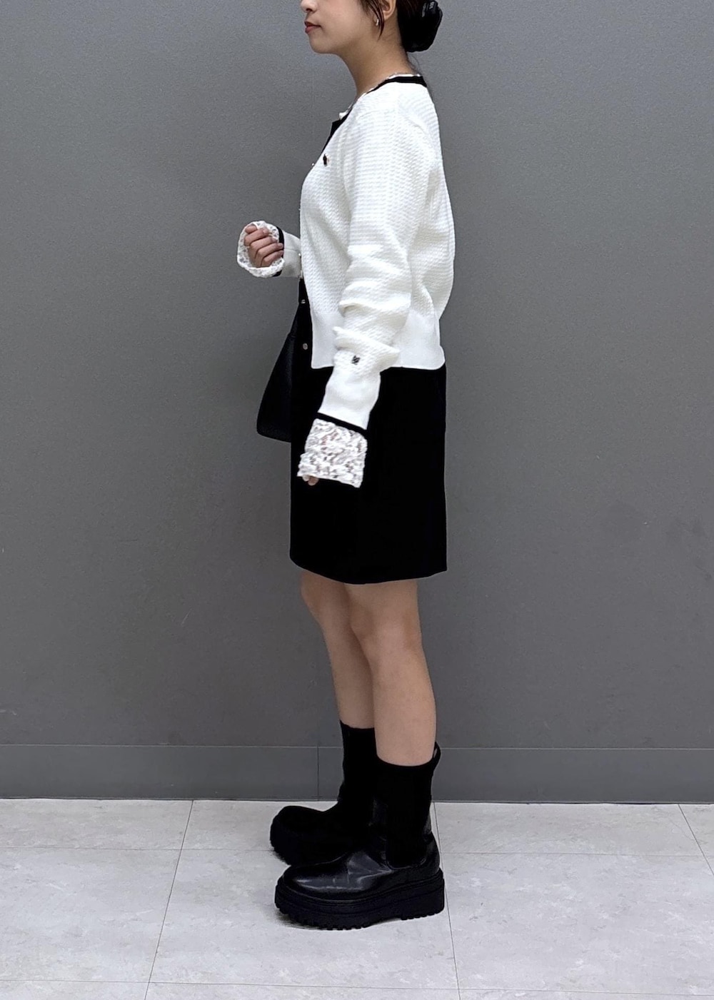 ブラック系のショルダーバッグ、ホワイト系のTシャツ/カットソー、ブラック系のブーツを着用したレディースの秋コーディネートの4枚目の写真