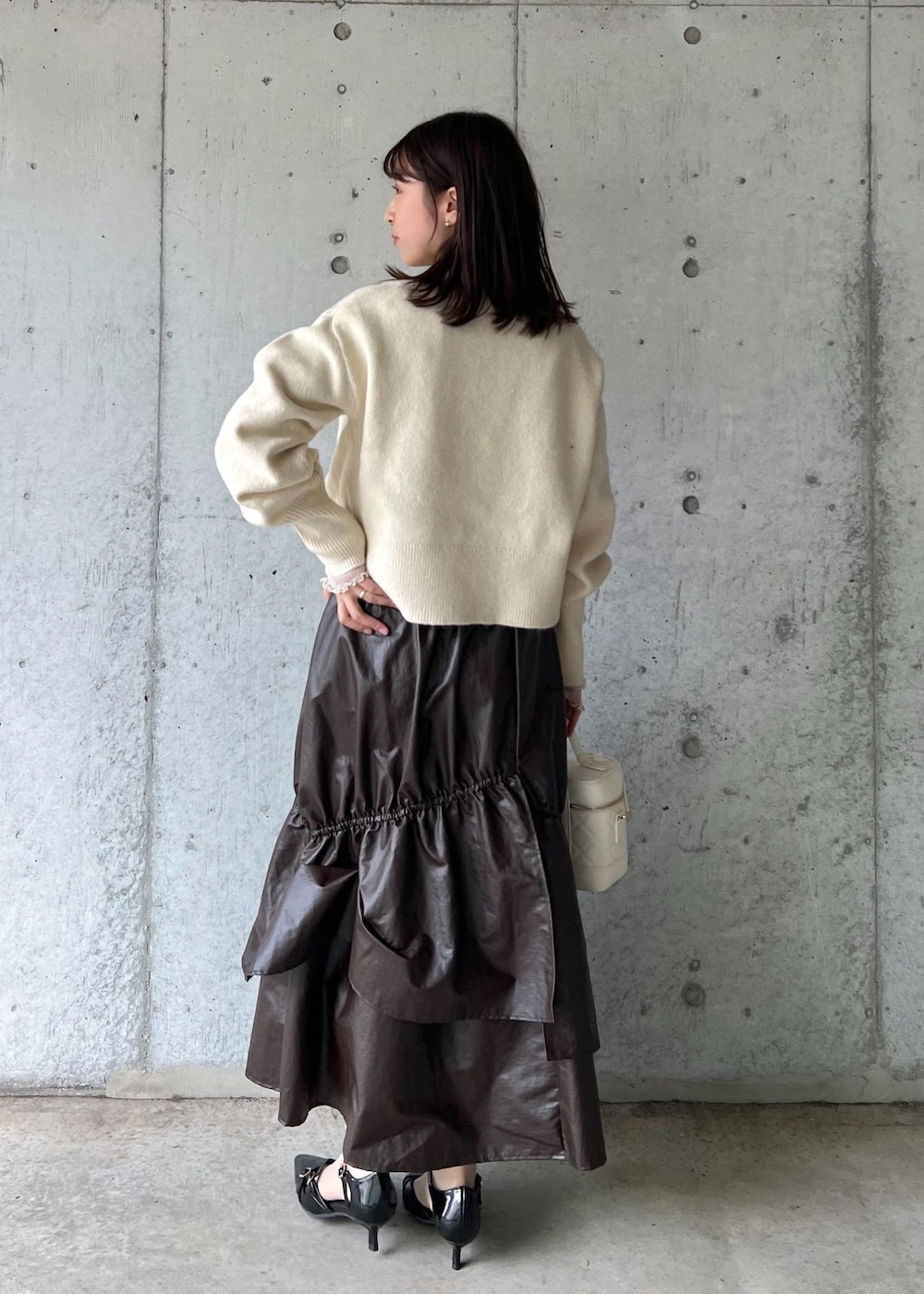 ブラウン系のスカート、ベージュ系のTシャツ/カットソー、ブラック系のパンプスを着用したレディースの冬コーディネートの4枚目の写真