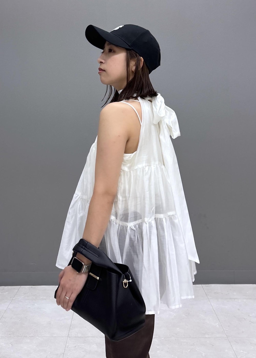 ブラック系のショルダーバッグ、ブラック系のパンプス、ホワイト系のシャツ/ブラウスを着用したレディースの夏コーディネートの6枚目の写真