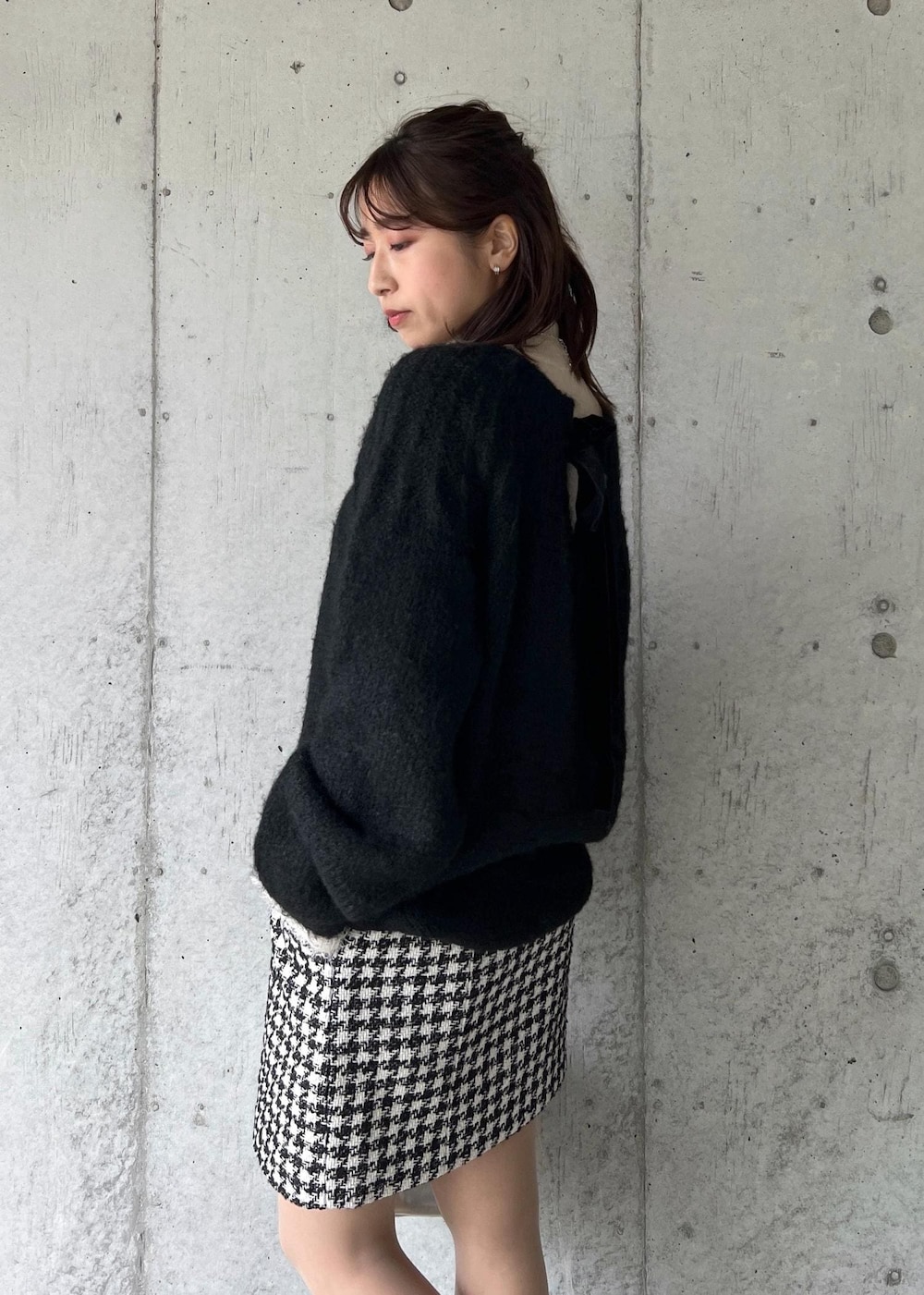 シルバー系のブーツ、ブラック系のスカート、ホワイト系のニット/セーターを着用したレディースの冬コーディネートの7枚目の写真