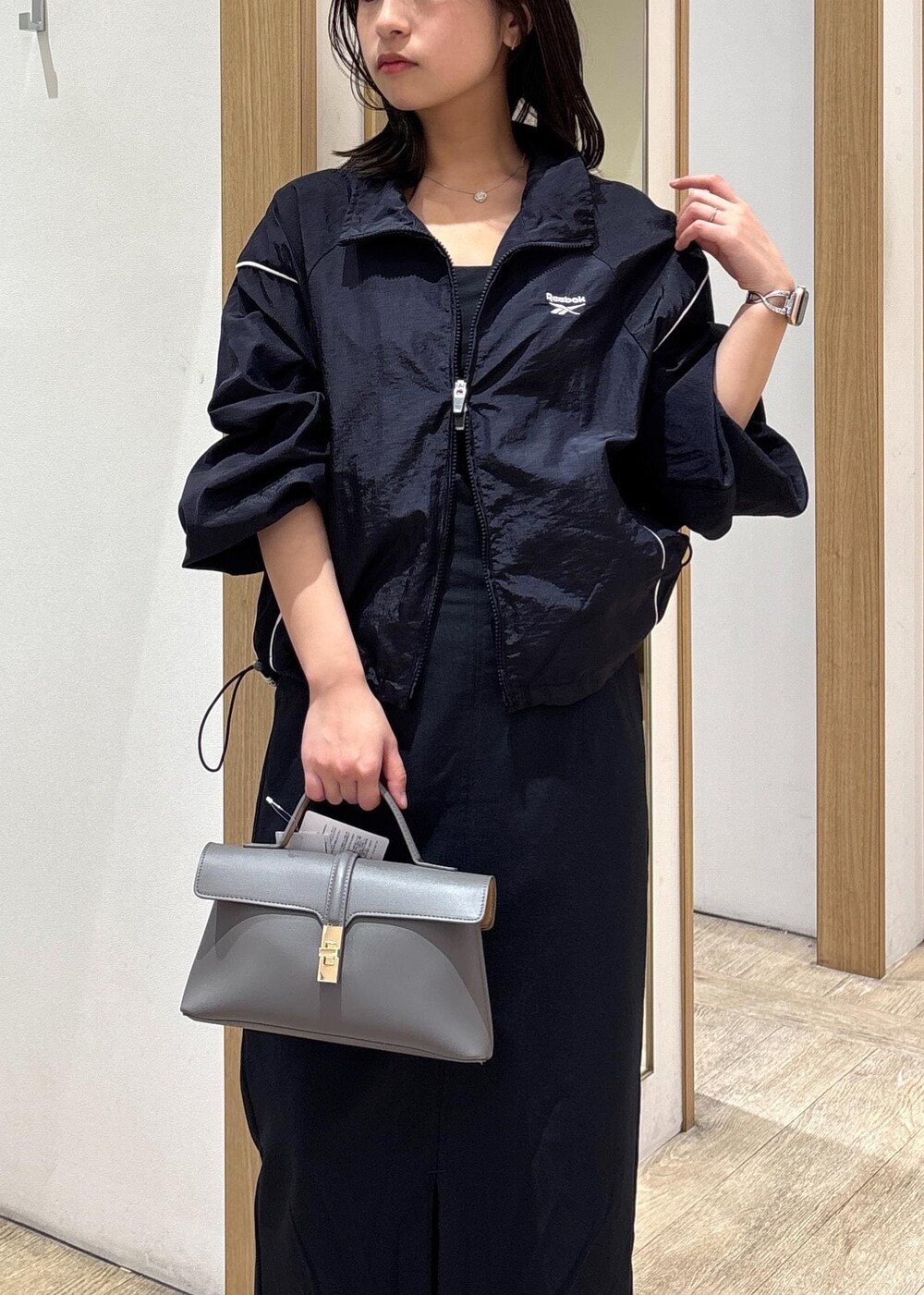 グレー系のショルダーバッグ、ブルー系のスカート、シルバー系のパンプスを着用したレディースの春コーディネートの5枚目の写真