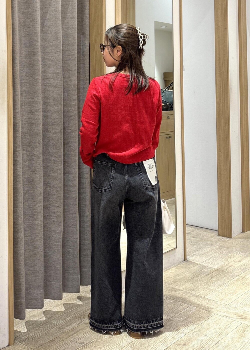 ブラウン系のパンプス、レッド系のカーディガン/ボレロ、ブラック系のデニムパンツを着用したレディースの春コーディネートの4枚目の写真