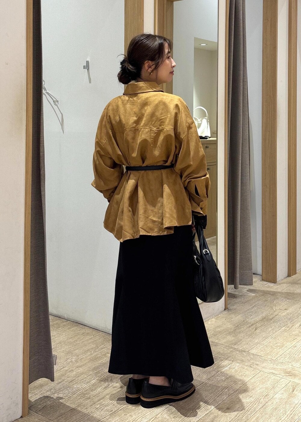 ブラック系のスカート、ブラック系のTシャツ/カットソー、ブラック系のハンドバッグを着用したレディースの秋コーディネートの3枚目の写真