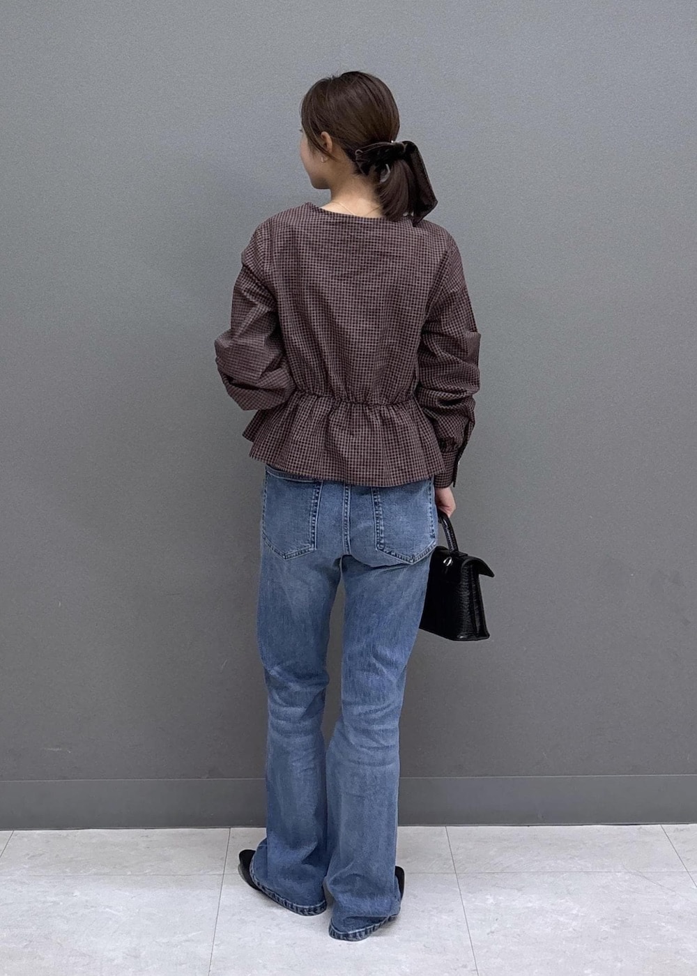 ブルー系のデニムパンツ、ブラック系のハンドバッグ、ブラック系のパンプスを着用したレディースの秋コーディネートの3枚目の写真