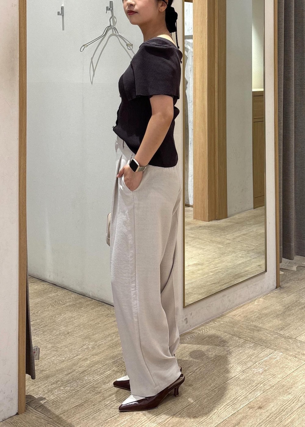 ブラウン系のパンプス、ホワイト系のスラックス、グレー系のニット/セーターを着用したレディースの秋コーディネートの2枚目の写真