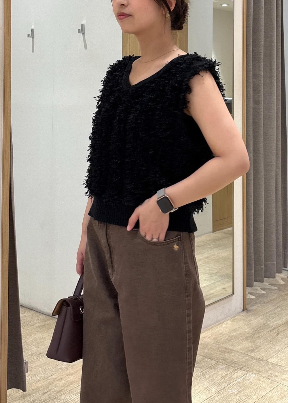 ブラウン系のショルダーバッグ、ブラック系のパンプス、ブラック系のベストを着用したレディースの秋コーディネートの7枚目の写真