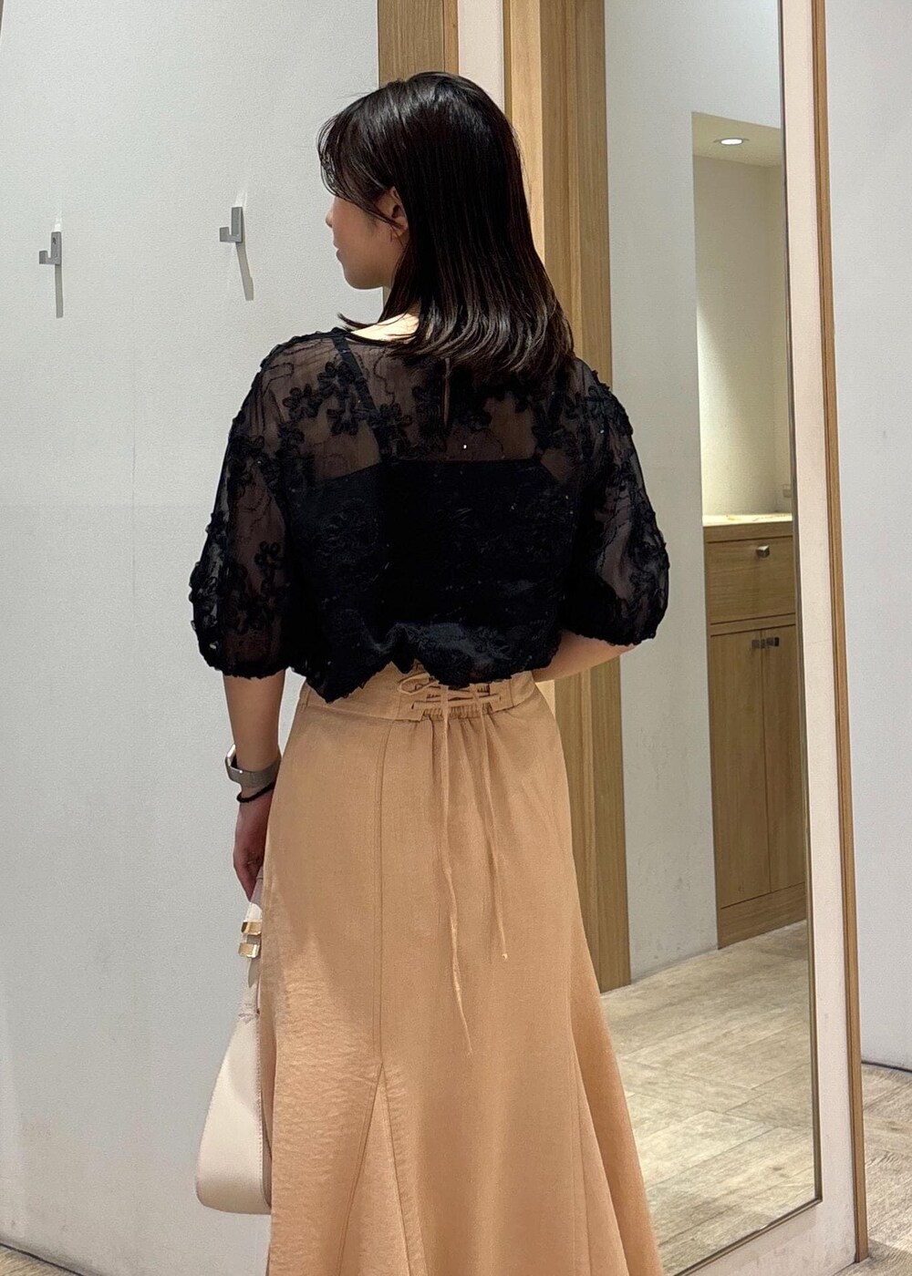 ホワイト系のハンドバッグ、シルバー系のパンプス、オレンジ系のスカートを着用したレディースの春コーディネートの8枚目の写真
