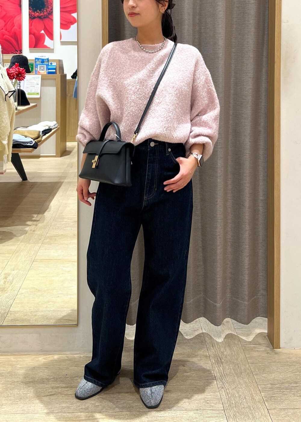 ブラック系のショルダーバッグ、シルバー系のブーツ、ブルー系のデニムパンツを着用したレディースの冬コーディネートの2枚目の写真