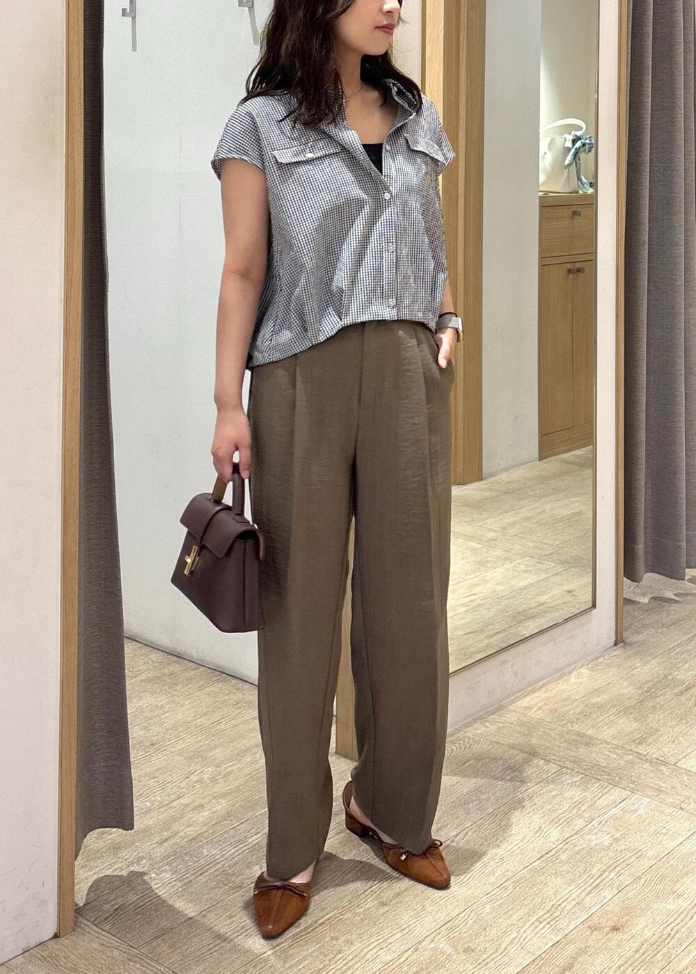 ブラウン系のショルダーバッグ、グリーン系のスラックス、ブラック系のシャツ/ブラウスを着用したレディースの夏コーディネートの9枚目の写真