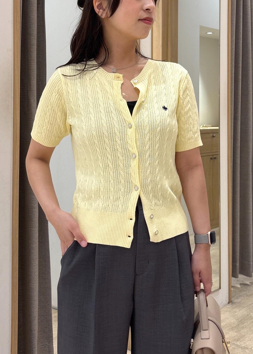 ベージュ系のショルダーバッグ、ブラック系のサンダル、グレー系のスラックスを着用したレディースの夏コーディネートの4枚目の写真