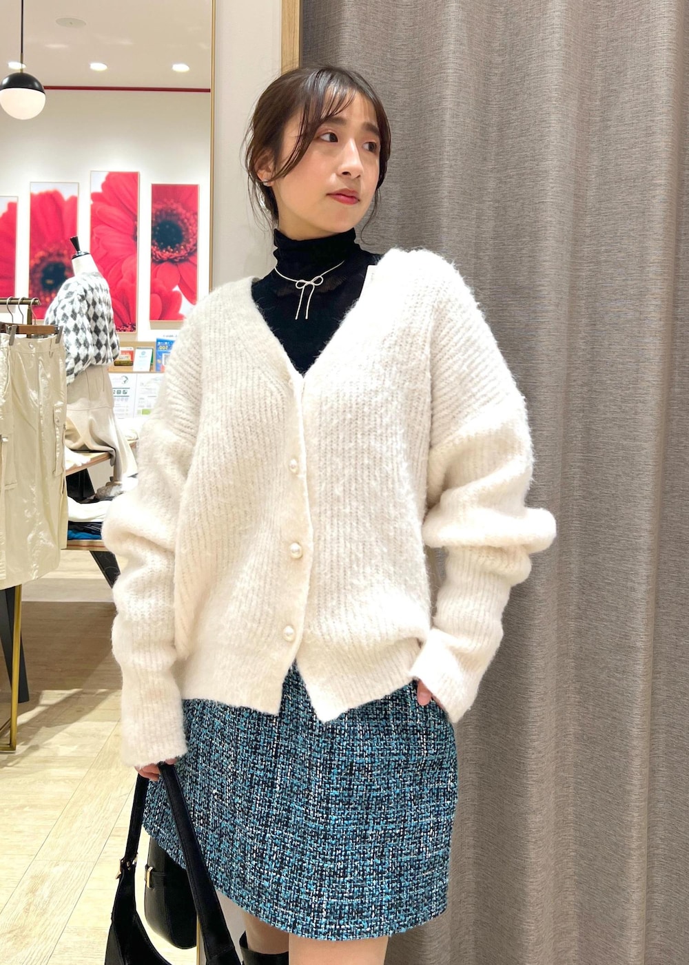 ブラック系のブーツ、ブルー系のスカート、ホワイト系のカーディガン/ボレロを着用したレディースの冬コーディネートの6枚目の写真