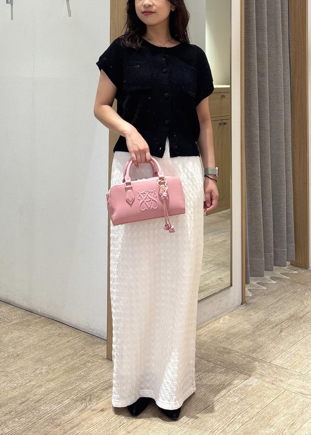 ホワイト系のスカート、ブラック系のカーディガン/ボレロ、ブラック系のパンプスを着用したレディースの夏コーディネートの9枚目の写真