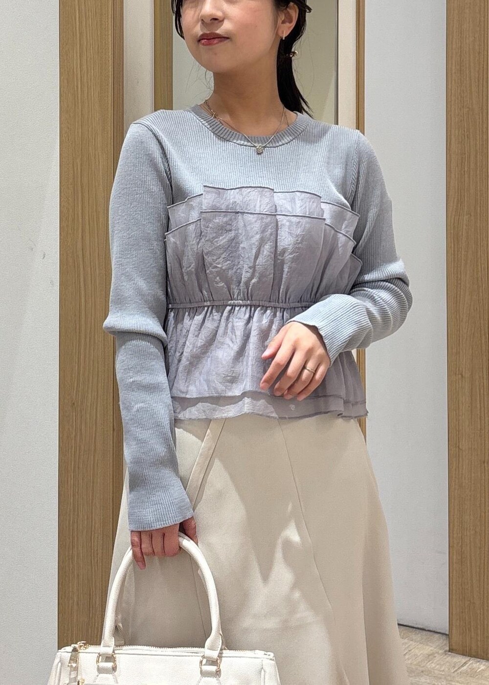 ブラック系のパンプス、ベージュ系のスカート、ブルー系のニット/セーターを着用したレディースの春コーディネートの6枚目の写真