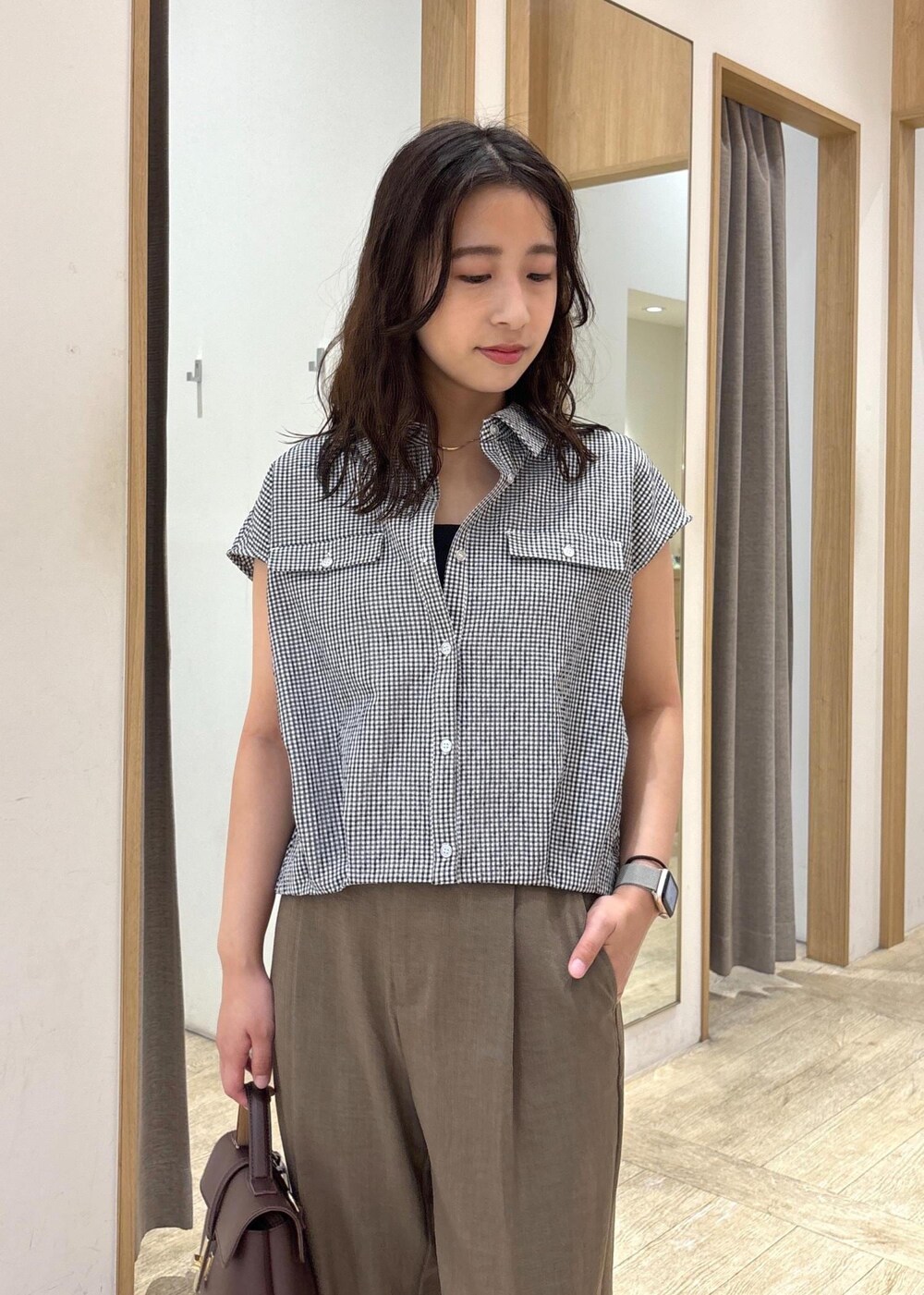 ブラウン系のショルダーバッグ、グリーン系のスラックス、ブラック系のシャツ/ブラウスを着用したレディースの夏コーディネートの4枚目の写真