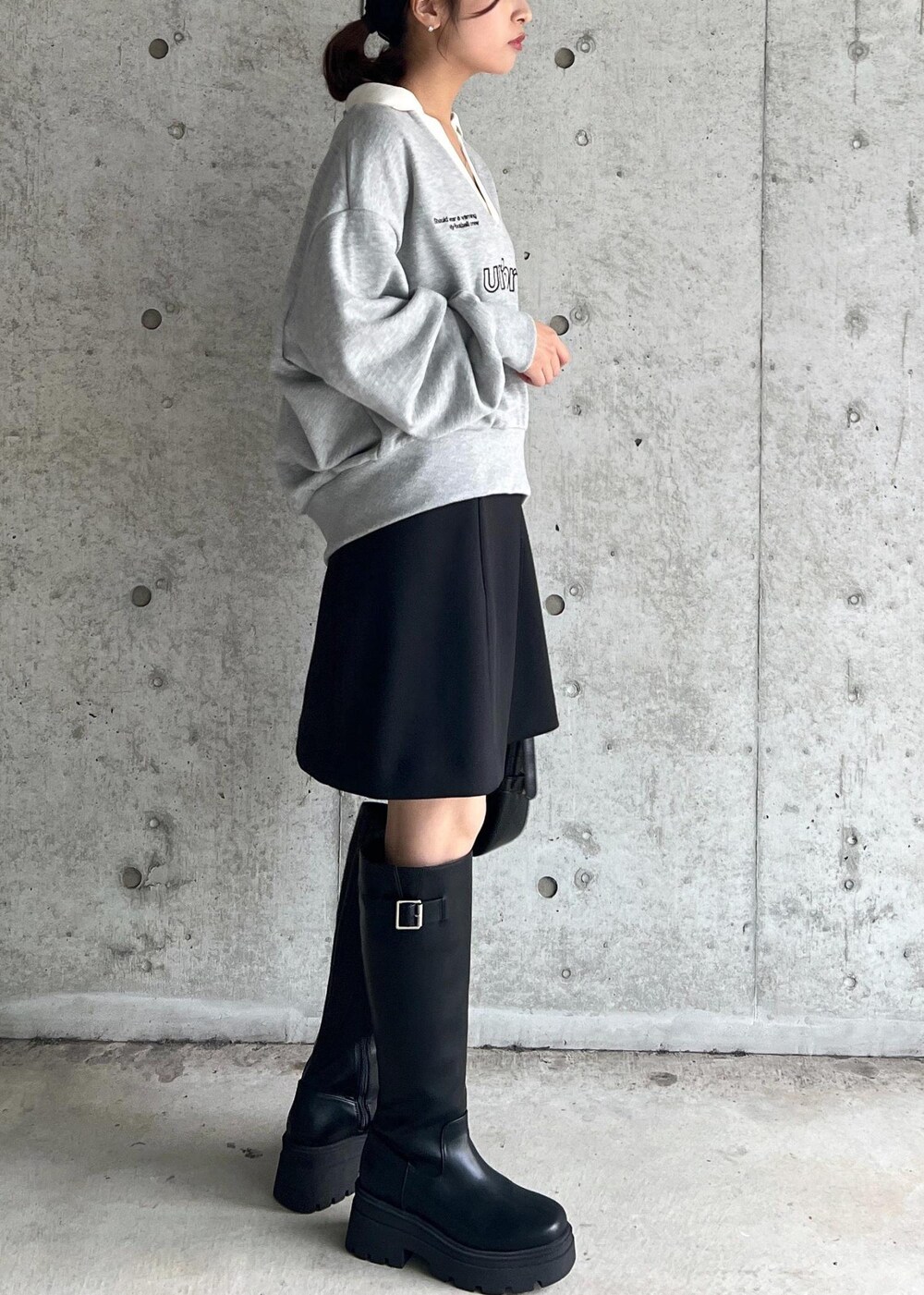 ブラック系のブーツ、ブラック系のハンドバッグ、ブラック系のスカートを着用したレディースの秋コーディネートの3枚目の写真