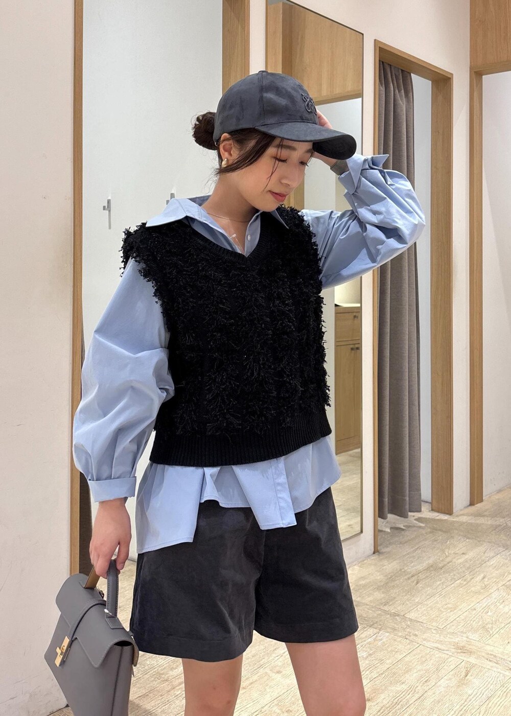 グレー系のショルダーバッグ、ブルー系のシャツ/ブラウス、ブラック系のベストを着用したレディースの秋コーディネートの5枚目の写真