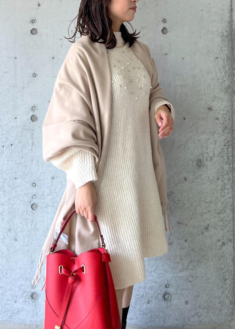 ブラウン系のブーツ、レッド系のショルダーバッグ、ホワイト系のワンピースを着用したレディースの冬コーディネートの7枚目の写真