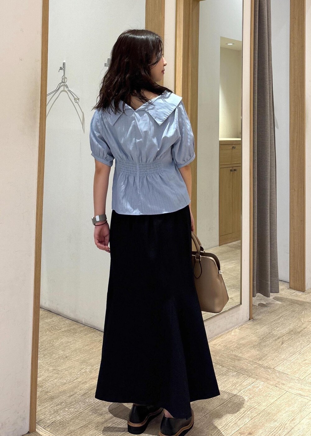 ベージュ系のボストンバッグ、ブラック系のスカート、ブラック系のローファーを着用したレディースの秋コーディネートの3枚目の写真