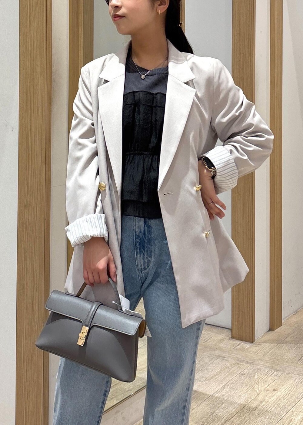 グレー系のショルダーバッグ、ベージュ系のテーラードジャケット、ブルー系のデニムパンツを着用したレディースの春コーディネートの5枚目の写真