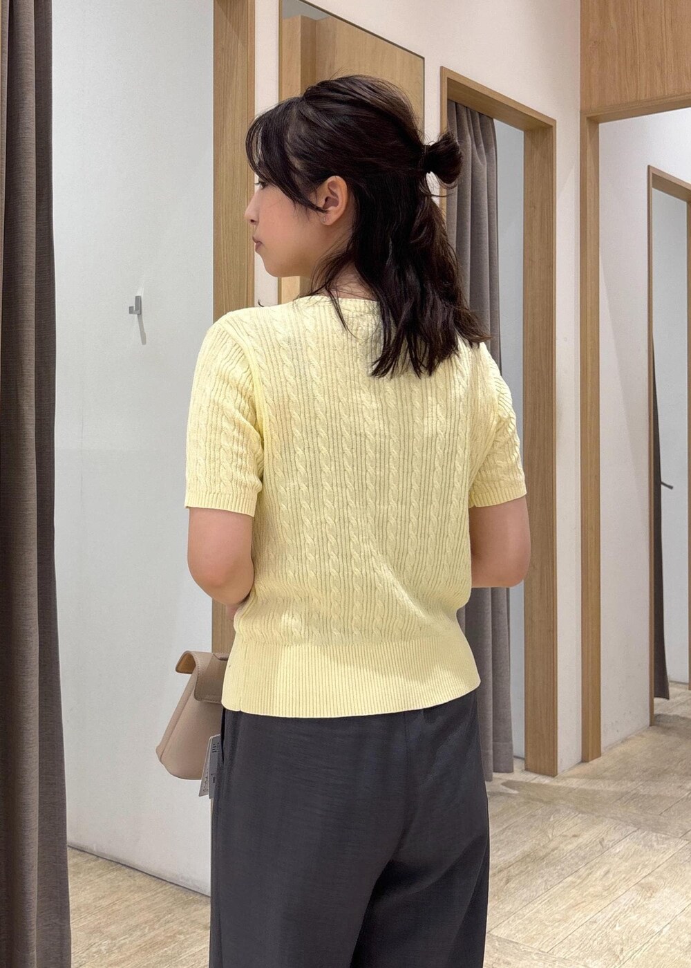 ベージュ系のショルダーバッグ、ブラック系のサンダル、グレー系のスラックスを着用したレディースの夏コーディネートの6枚目の写真