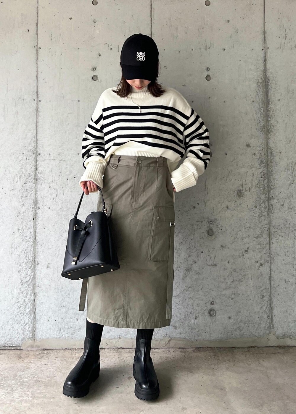 ブラック系のブーツ、グリーン系のスカート、ホワイト系のニット/セーターを着用したレディースの秋コーディネートの2枚目の写真