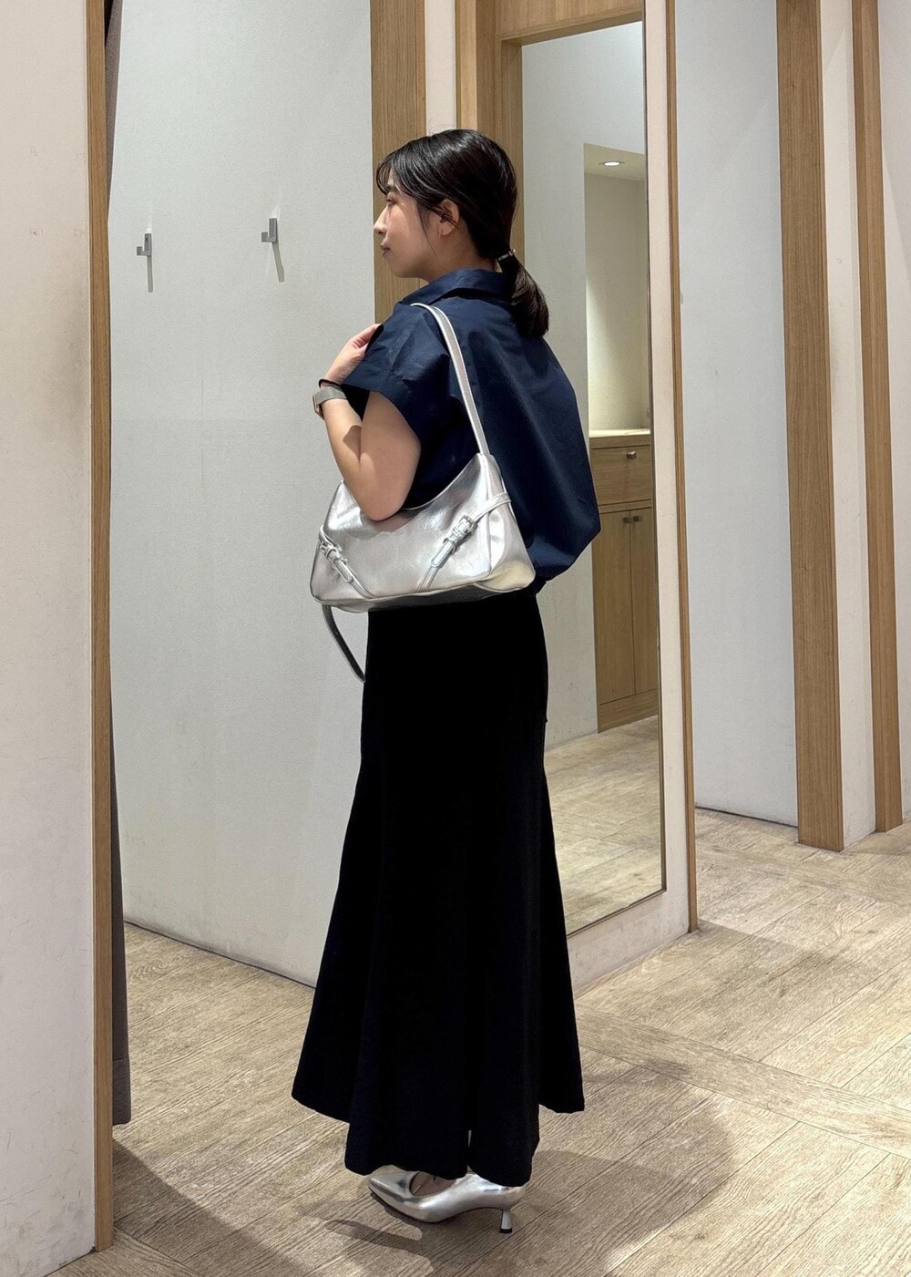 ホワイト系のキャミソール、シルバー系のパンプス、ブラック系のスカートを着用したレディースの春コーディネートの2枚目の写真