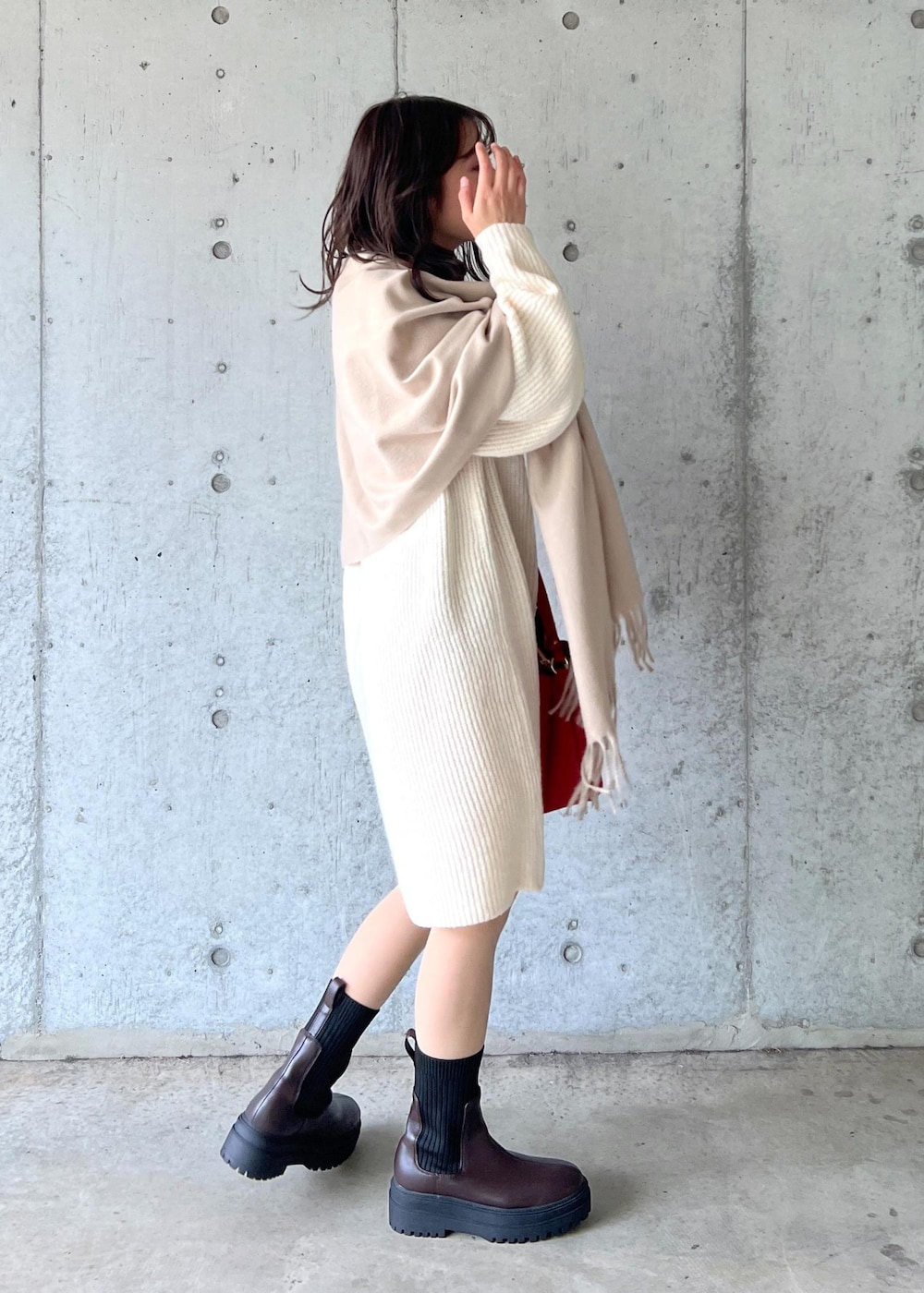 ブラウン系のブーツ、レッド系のショルダーバッグ、ホワイト系のワンピースを着用したレディースの冬コーディネートの5枚目の写真