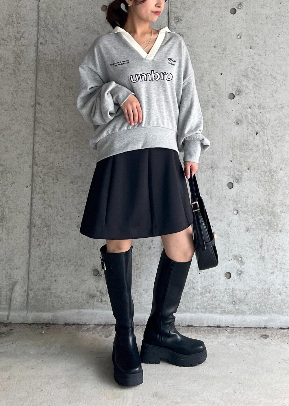 ブラック系のブーツ、ブラック系のハンドバッグ、ブラック系のスカートを着用したレディースの秋コーディネートの2枚目の写真