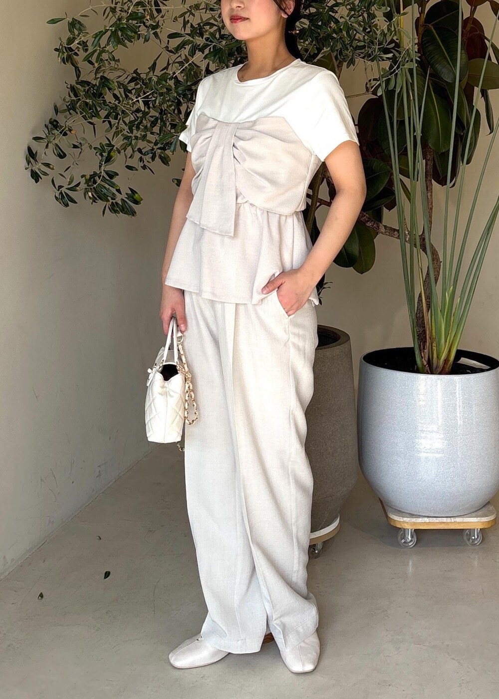 ホワイト系のパンプス、ホワイト系のTシャツ/カットソー、ホワイト系のスラックスを着用したレディースの春コーディネートの2枚目の写真