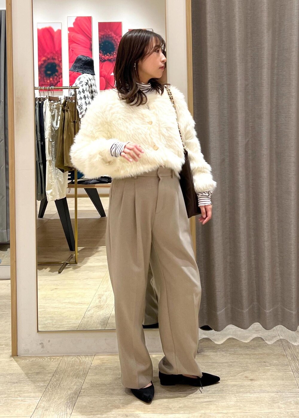 ベージュ系のスラックス、ホワイト系のカーディガン/ボレロ、ブラウン系のショルダーバッグを着用したレディースの冬コーディネートの2枚目の写真